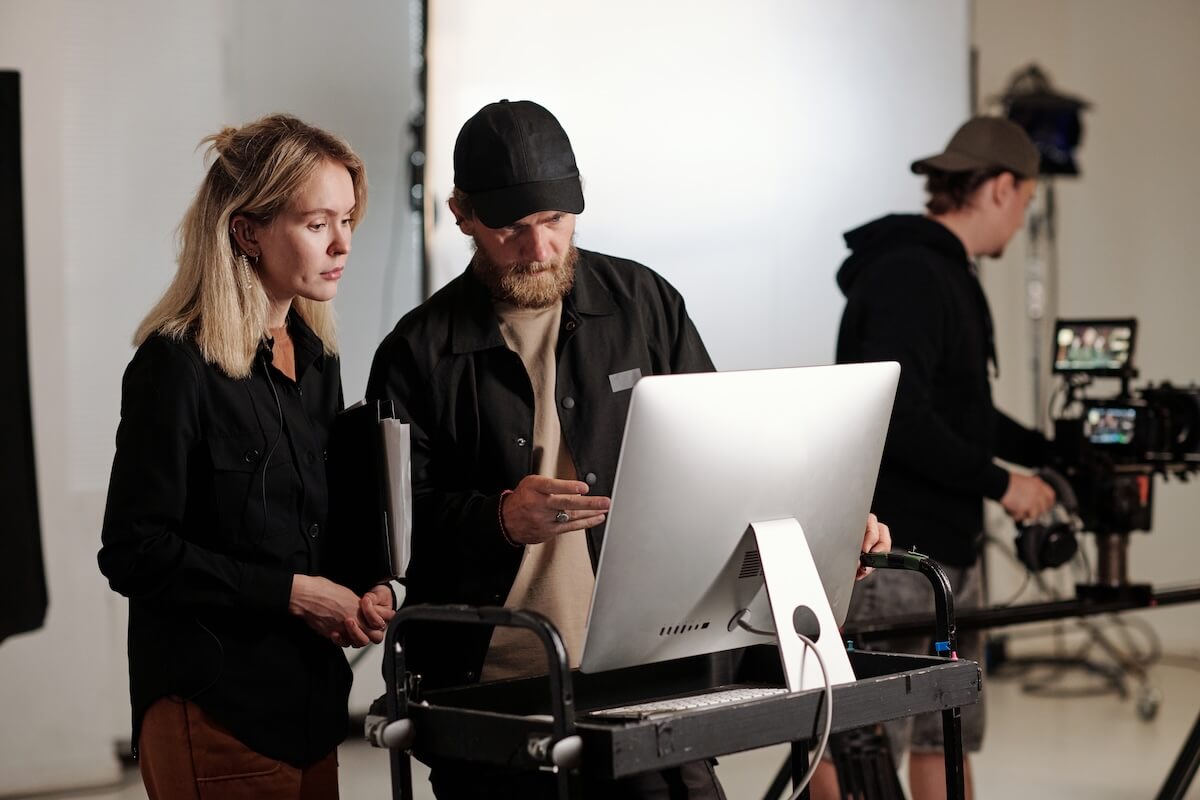 Young videographer and his assistant having discussion in front of computer Hybrid cloud